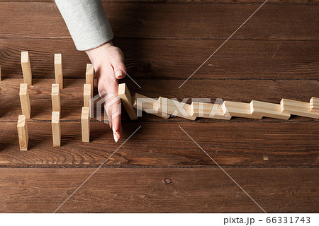 Businesswoman protecting dominoes from falling 66331743