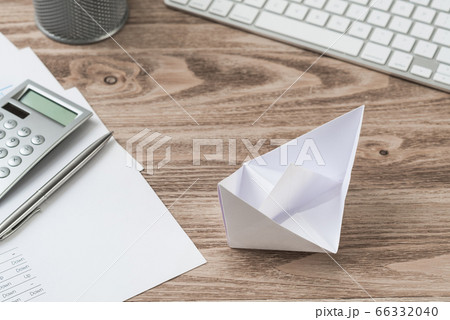 Wooden office desk with white origami boat. Wooden office desk with white origami boat. 66332040