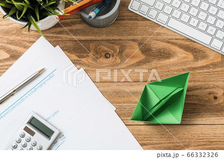 Wooden office desk with green origami boat. 66332326