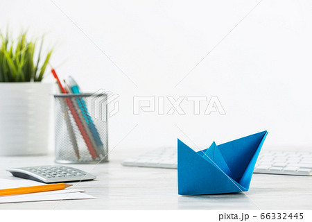 Wooden office desk with deep blue origami boat Wooden office desk with deep blue origami boat 66332445