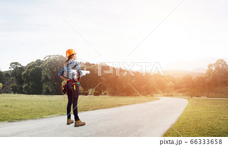 Young woman in safety helmet standing on road Young woman in safety helmet standing on road 66333658