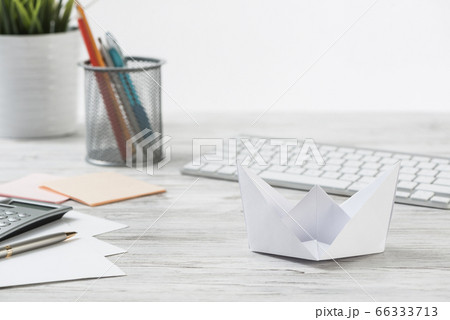 Wooden office desk with white origami boat Wooden office desk with white origami boat 66333713