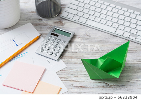 Modern office workspace with green paper ship 66333904