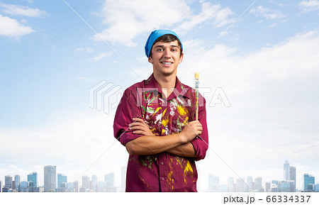 Smiling young painter artist holding paintbrush 66334337