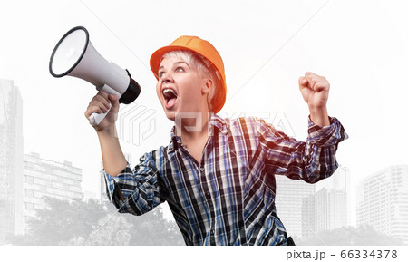 Expressive woman in helmet shouting into megaphone Expressive woman in helmet shouting into megaphone 66334378