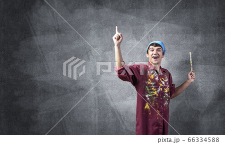 Young emotional artist gesturing with paintbrush Young emotional artist gesturing with paintbrush 66334588