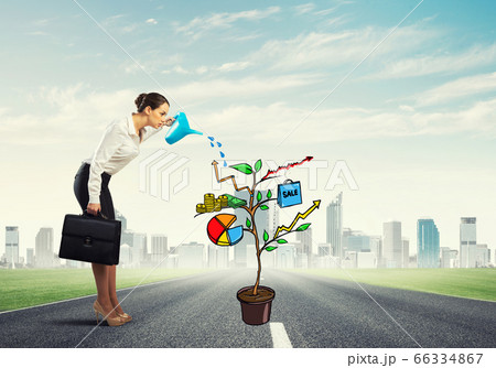 Young businesswoman outdoors watering drawn growth concept with 66334867