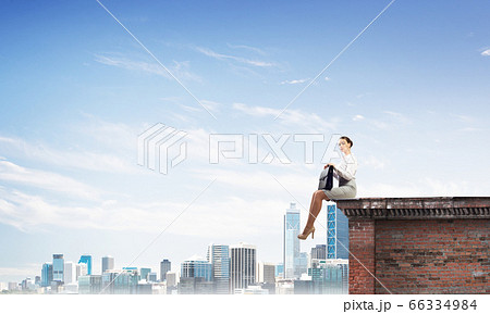 Businesswoman or accountant on brick roof against modern city scape 66334984