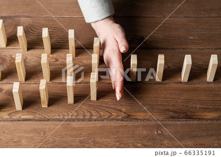 Businesswoman protecting dominoes from falling 66335191