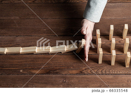 Businesswoman protecting dominoes from falling Businesswoman protecting dominoes from falling 66335548