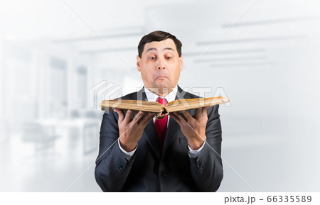 Surprised businessman holding open book 66335589