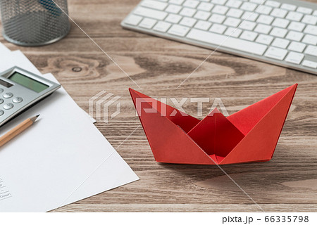 Businessman workspace at desk with red paper ship 66335798