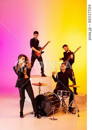Young caucasian musicians, band performing in neon light on gradient studio background Young caucasian musicians, band performing in neon light on gradient studio background 66337504