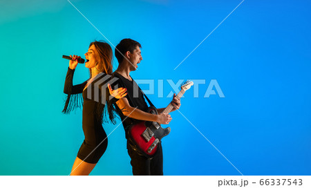 Caucasian musicians, singer and guitarist, isolated on blue studio background in neon light Caucasian musicians, singer and guitarist, isolated on blue studio background in neon light 66337543