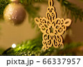 A wooden star shaped Christmas Tree Decoration hanging from a tree 66337957