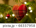 A fabric heart shaped Christmas Tree Decoration hanging from a tree 66337958