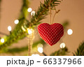 A fabric heart shaped Christmas Tree Decoration hanging from a tree 66337966