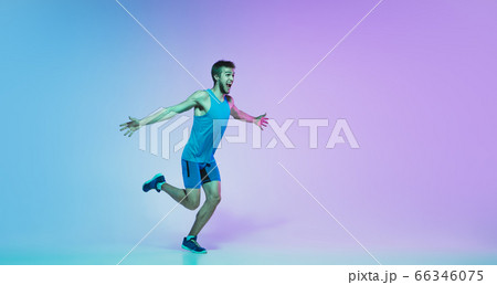 Full length portrait of active young caucasian running, jogging man on gradient studio background in neon light Full length portrait of active young caucasian running, jogging man on gradient studio background in neon light 66346075