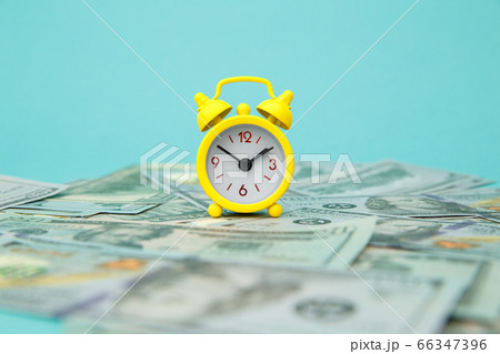 Close-up of yellow alarm clock and money on blue background. Business Finance and Money concept. Save money for prepare in the future. Time is money concept 66347396