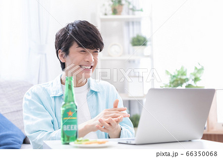 ノートパソコンでオンライン飲み会に参加する若い男性 66350068