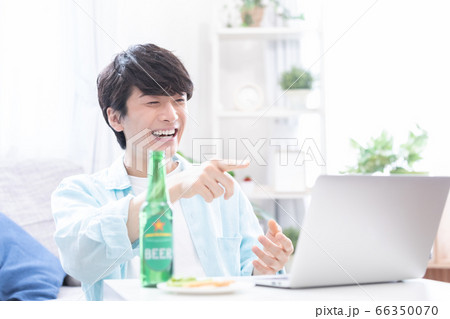 ノートパソコンでオンライン飲み会に参加する若い男性 66350070