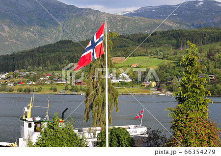 ノルウェー ハダンゲルフィヨルド、ウルヴィク地区の波止場の遊覧船とはためくノルウェーの国旗 ノルウェー ハダンゲルフィヨルド、ウルヴィク地区の波止場の遊覧船とはためくノルウェーの国旗 66354279