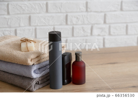 Stack of towels and man toiletries on wooden table. 66356530