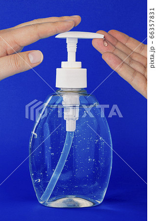 A close up of a person applying hand sanitizer on a dark blue background 66357831