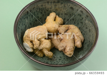 Raw ginger root spice in green bowl on light green background Raw ginger root spice in green bowl on light green background 66359493
