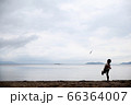 砂浜でおもちゃの飛行機を飛ばす男の子のシルエット 66364007