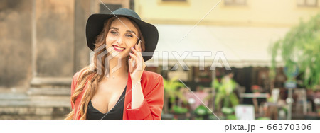 Woman is talking by phone in city street outdoors 66370306