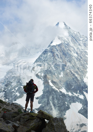 Male tourist climbing snowy rocky cliffs of beautiful Penning Alps in Switzerland Male tourist climbing snowy rocky cliffs of beautiful Penning Alps in Switzerland 66374340