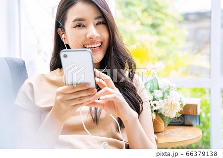 美人　女性　自宅　室内　リビング　ソファ　携帯　電話　使う　音楽　チャット　楽しむ　人物　素材 66379138