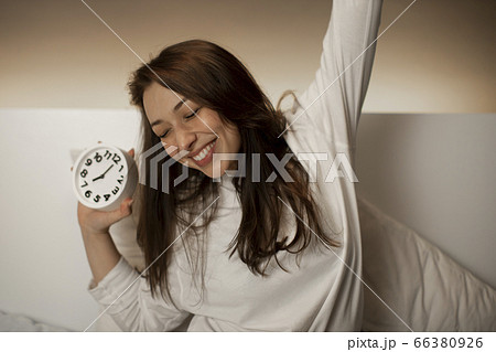 Cute Caucasian girl with dark hair wakes up from an alarm clock and stretches 66380926