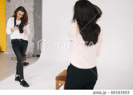 Woman photographer and female model together looking at made photo on camera screen. 66383605