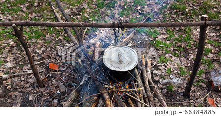 Cooking in old sooty cauldron on campfire at glade 66384885