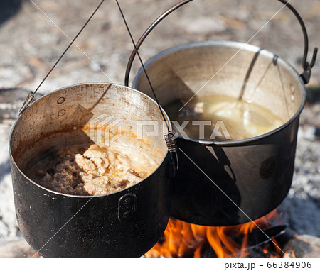 Cooking in two sooty old pots on bonfire at sunny 66384906