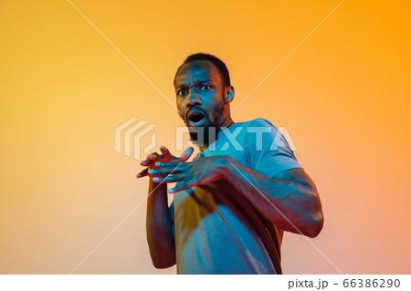 African-american man's portrait isolated on gradient orange studio background in neon light African-american man's portrait isolated on gradient orange studio background in neon light 66386290
