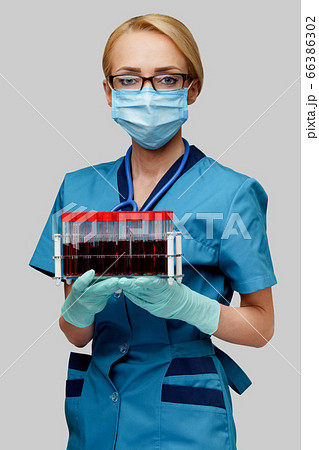 medical doctor nurse woman wearing protective mask and gloves - holding rack with virus blood tests 66386302