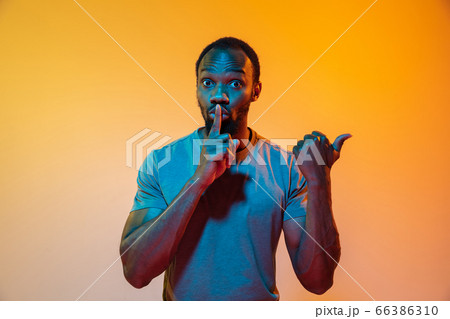 African-american man's portrait isolated on gradient orange studio background in neon light African-american man's portrait isolated on gradient orange studio background in neon light 66386310