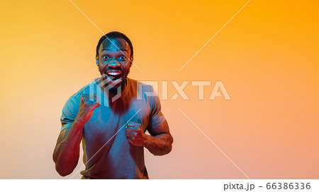 African-american man's portrait isolated on gradient orange studio background in neon light African-american man's portrait isolated on gradient orange studio background in neon light 66386336