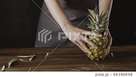Woman' hands with ripe juicy natural organic tropical fruit pineapple on a wooden kitchen table on a black background. Woman' hands with ripe juicy natural organic tropical fruit pineapple on a wooden kitchen table on a black background. 66386698