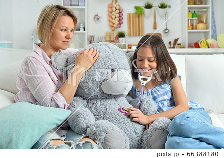 Girl and mother playing with toy bear in facial mask. Girl with stethoscope Girl and mother playing with toy bear in facial mask. Girl with stethoscope 66388180