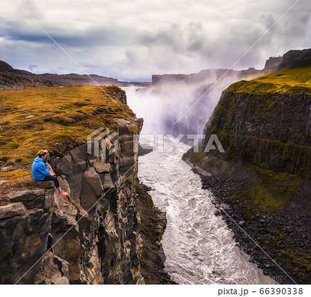 Hiker sitting at the edge of the Gullfoss waterfall in Iceland Hiker sitting at the edge of the Gullfoss waterfall in Iceland 66390338