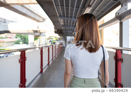 Young Asian woman wearing surgical mask walking in city 66390429