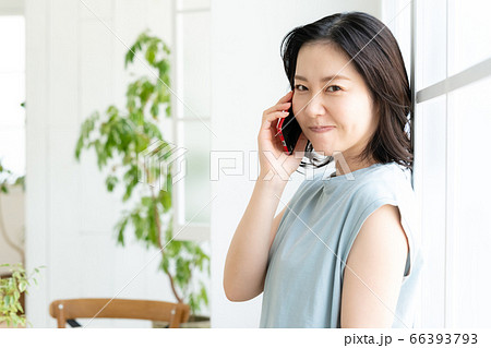スマホで通話するミドル女性【リビング】 スマホで通話するミドル女性【リビング】 66393793