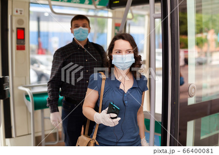 Brunette in medical mask getting off tram Brunette in medical mask getting off tram 66400081