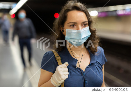 Woman in mask with earphones on subway station 66400108