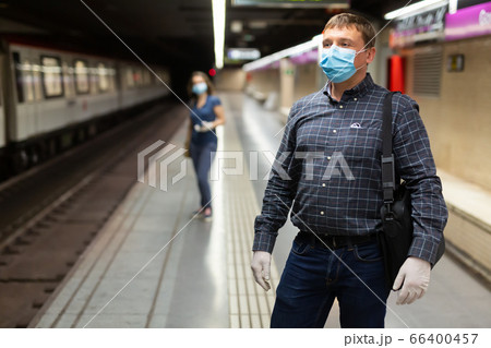 Man in protective medical mask is standing on platform and waiting train in the underground. 66400457