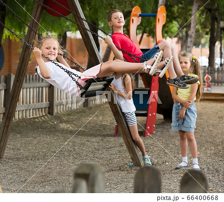Small girls and boys swinging on playground 66400668